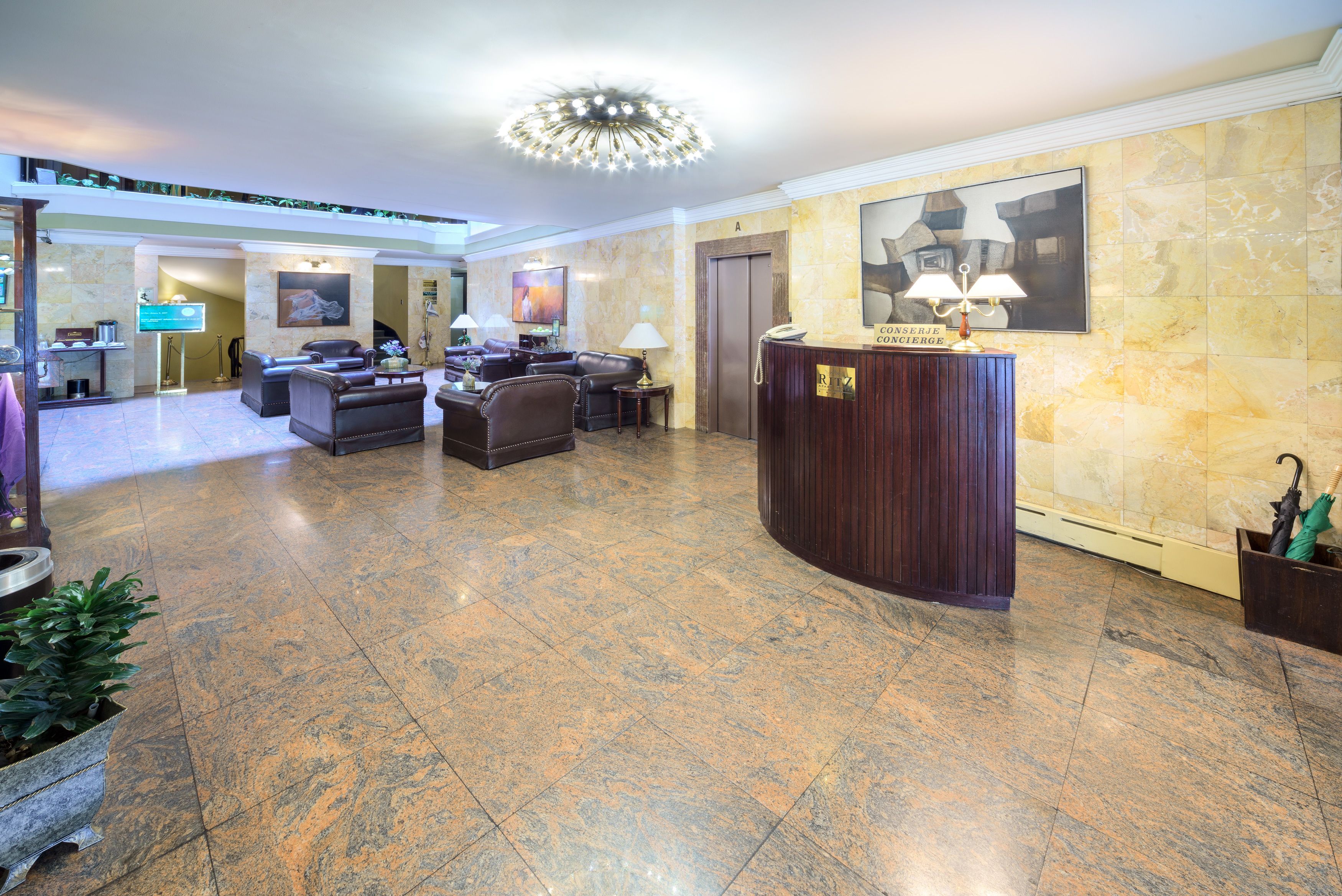A spacious lobby with a reception desk, seating area, and a large chandelier.