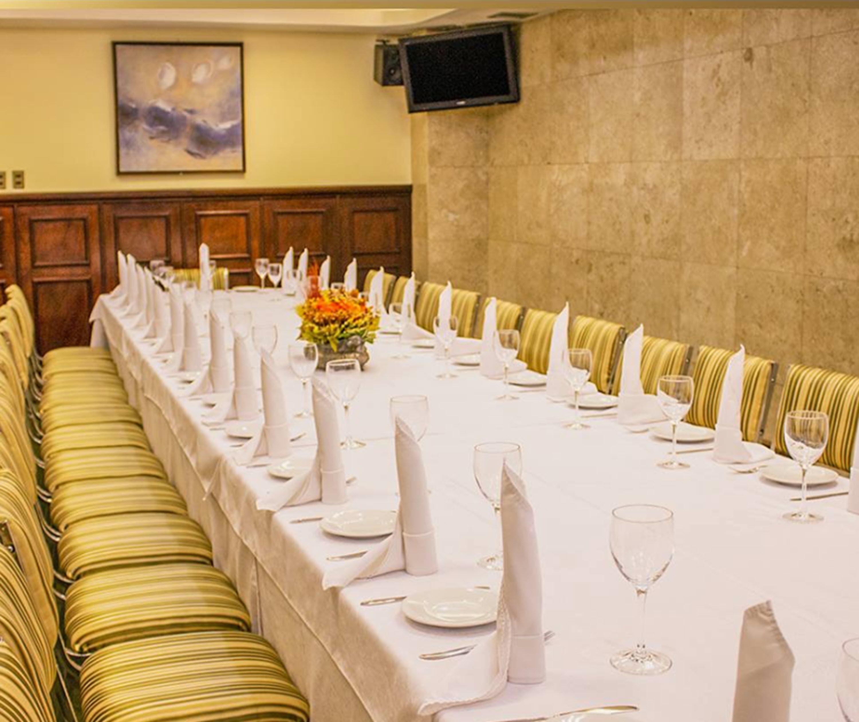 A long dining table set for a formal event, with neatly folded white napkins, wine glasses, and a centerpiece.