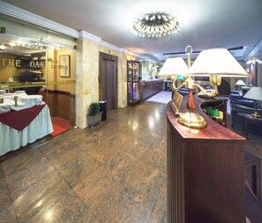 A hotel lobby with a reception desk, a bar, and a dining area.