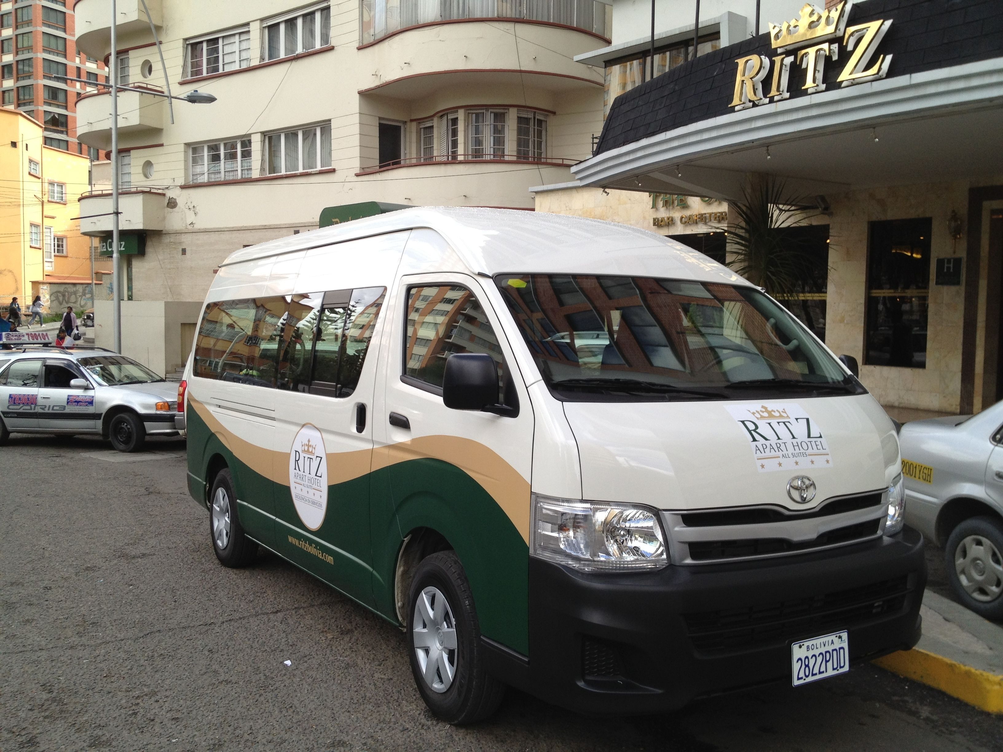 A white and green van parked in front of the Ritz Apart Hotel.