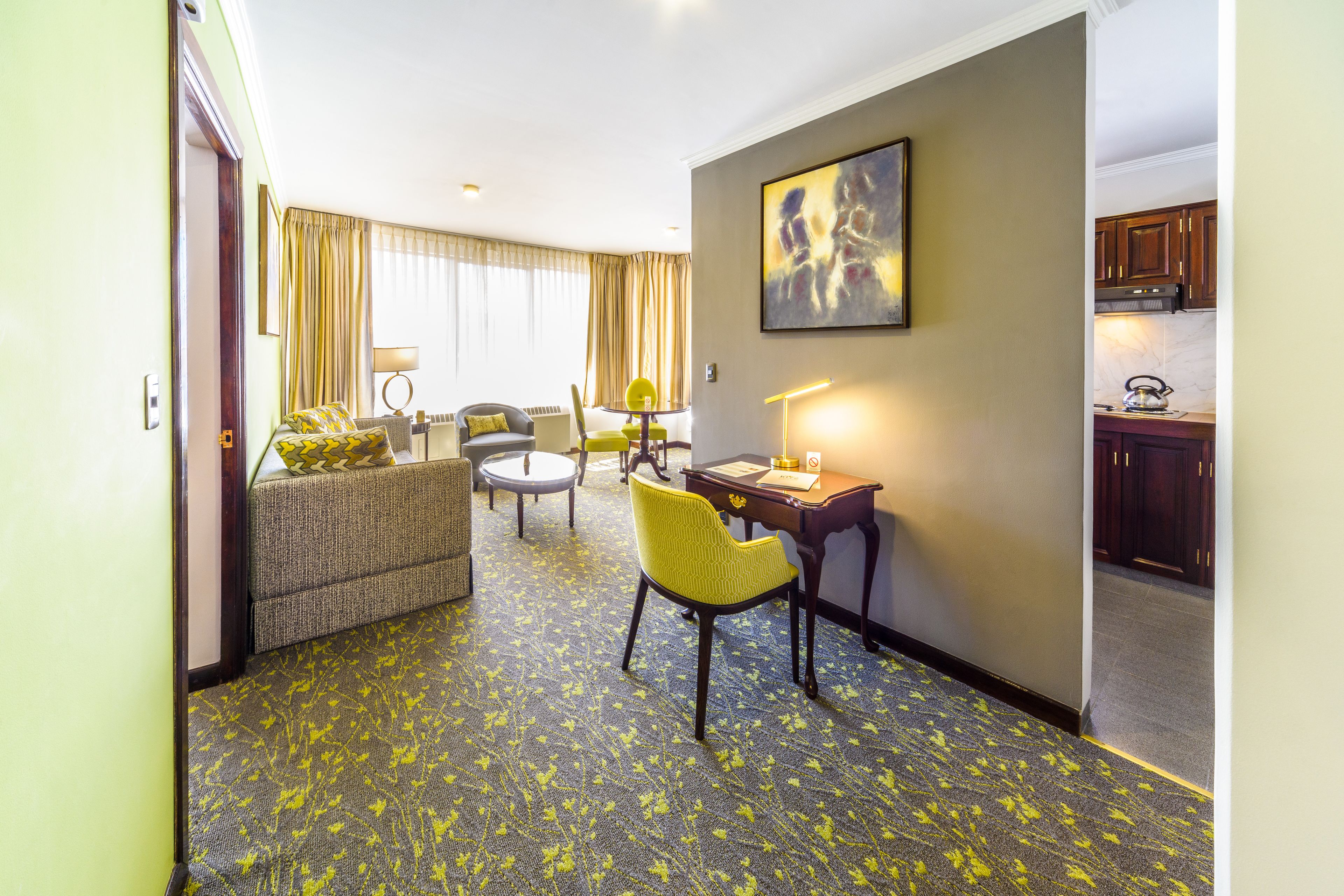 A hotel room with a living area, a dining table, and a kitchen.