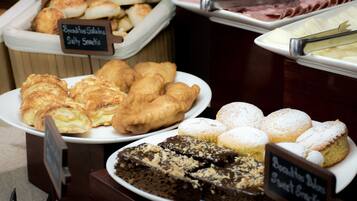 Un bufé con diversas opciones de panadería, incluyendo pasteles, pan y postres.