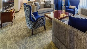 A hotel room with a living area featuring a sofa, armchairs, a coffee table, and a television. - Ritz Apart Hotel (La Paz)