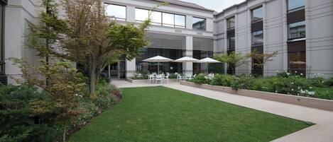 A courtyard with a lawn, outdoor seating, and a building with large windows.