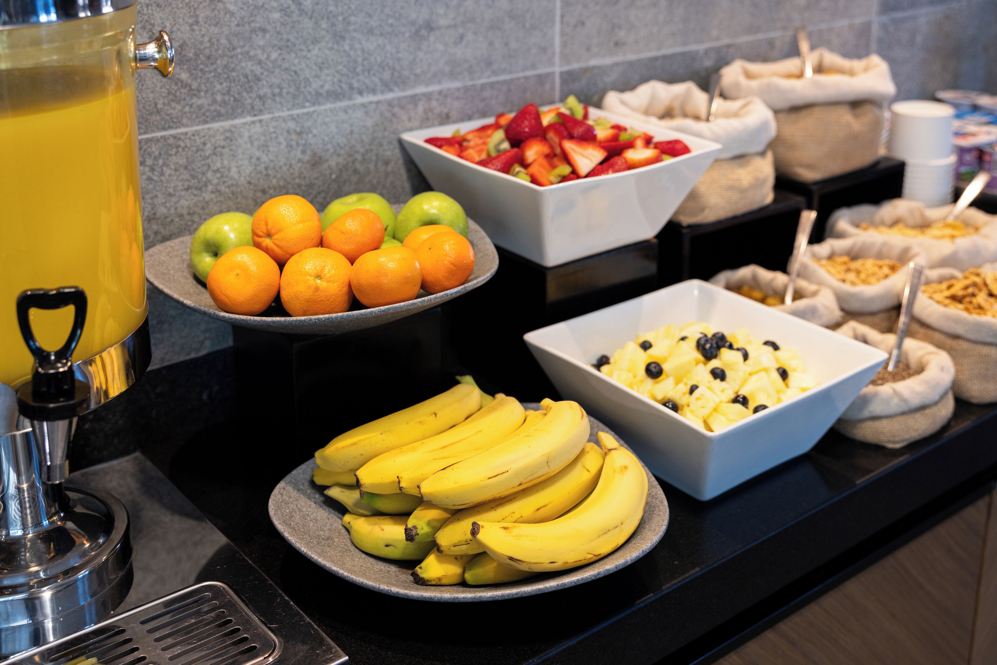 A buffet with various fruits and a punch dispenser.