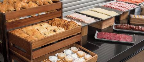 A buffet with various food items including pastries, meats, and desserts.