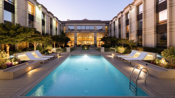 A swimming pool with lounge chairs and a building in the background.