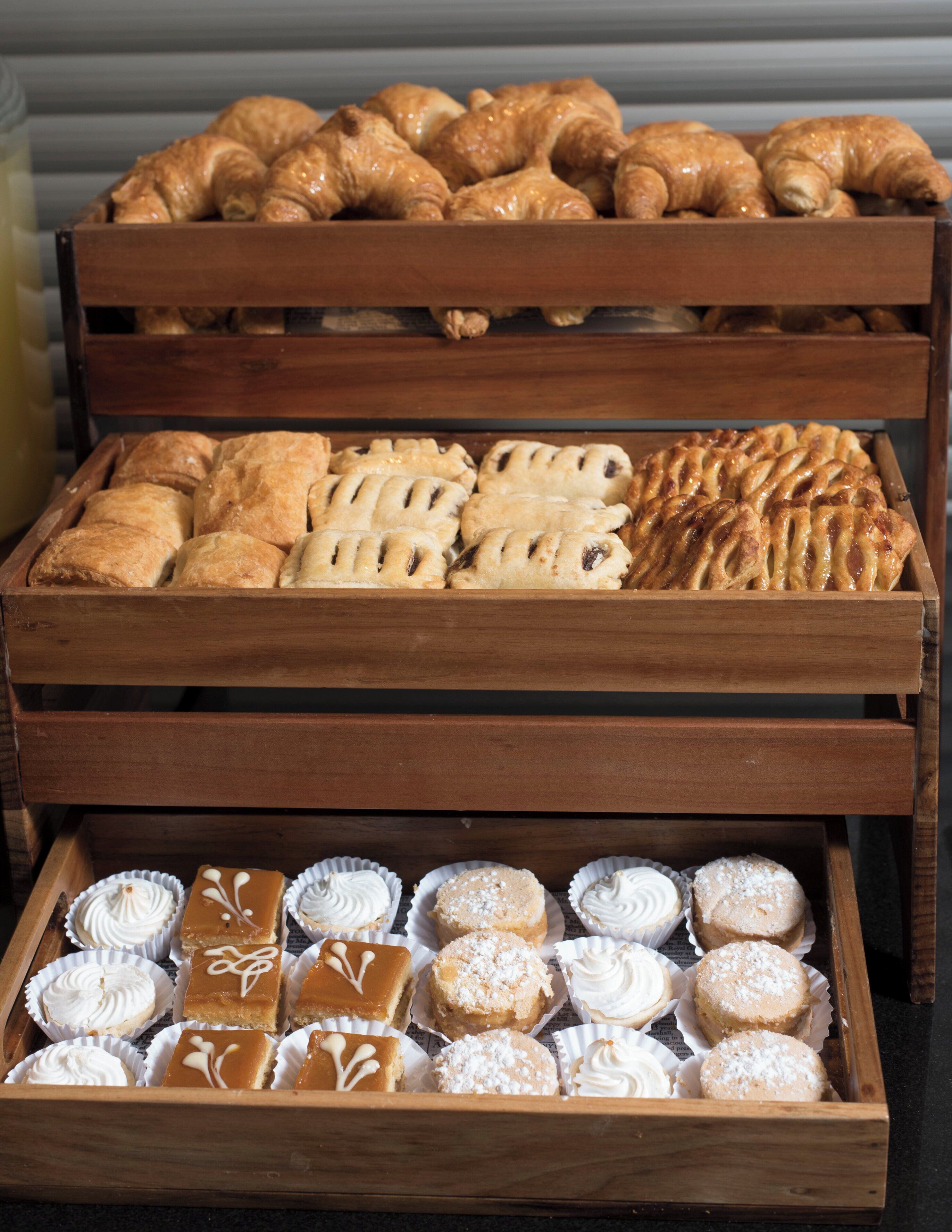 Un expositor de madera con diversas opciones de panadería, incluyendo pasteles y postres.