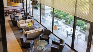 A spacious indoor seating area with multiple sofas and armchairs, a glass coffee table, and a view of the outdoor patio area through large windows.