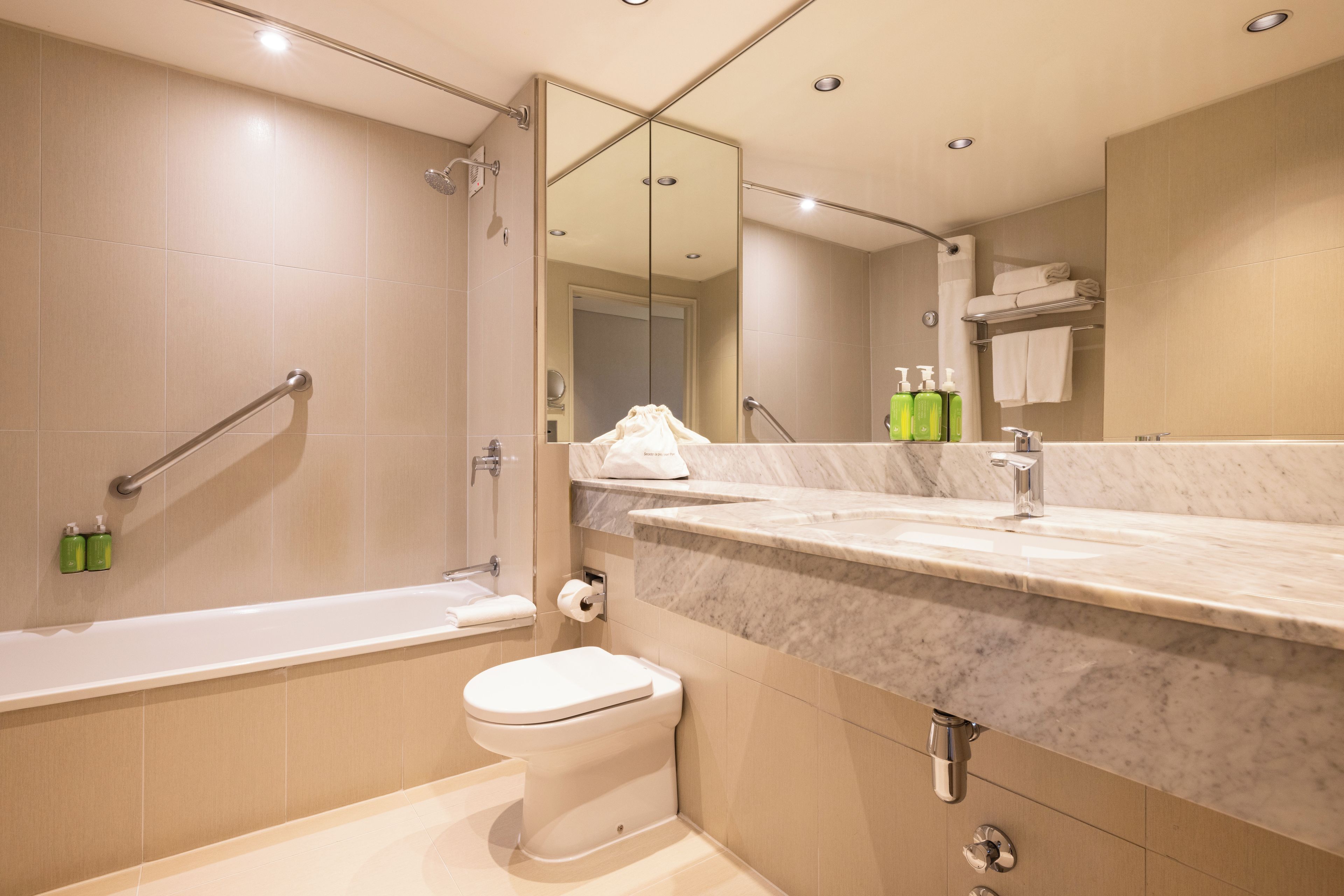 A modern bathroom with a bathtub, toilet, and a large mirror.