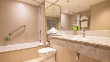 A modern bathroom with a bathtub, toilet, and a large mirror.