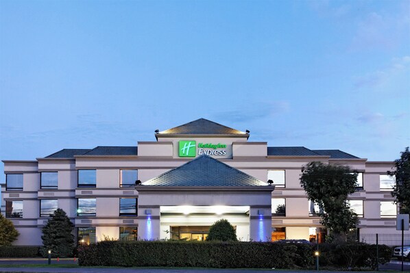 A Holiday Inn Express hotel with a modern design, featuring a prominent sign, a central entrance, and a symmetrical facade.