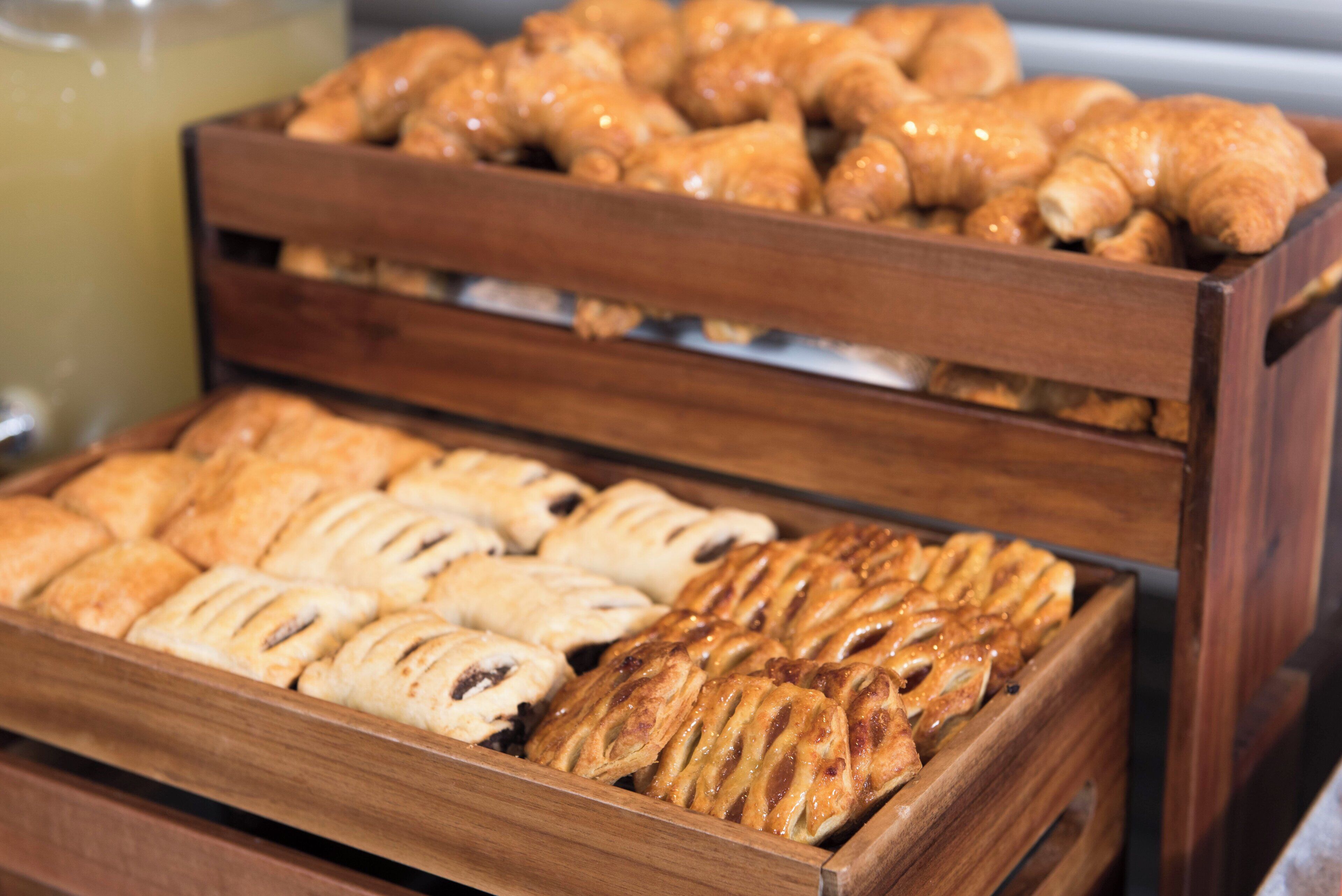 A wooden display case with various baked goods, including pastries and bread.