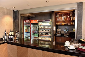 A hotel lobby with a reception desk, a Coca-Cola refrigerator, a chilled beverage display, and a coffee machine. - Holiday Inn Express Concepcion by IHG (Concepción)
