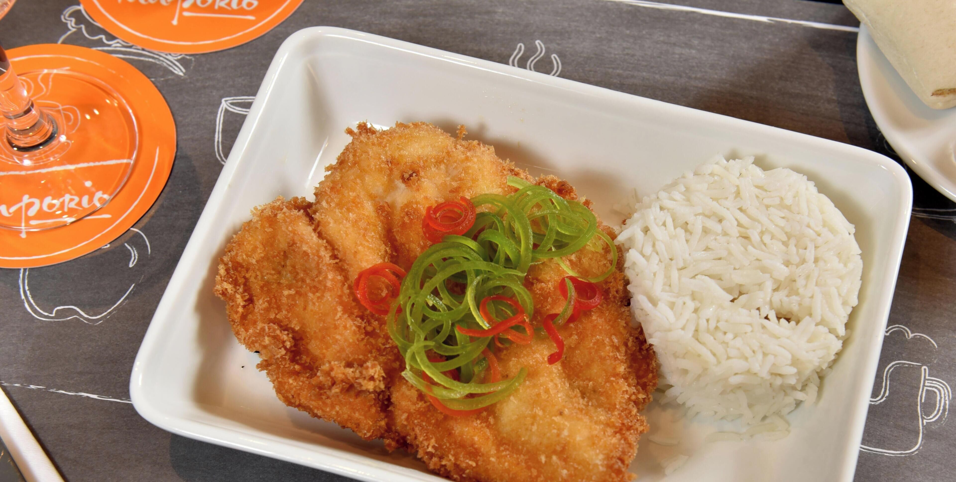 Een bord met gepaneerde kipnuggets, gesneden groene en rode paprika en witte rijst.