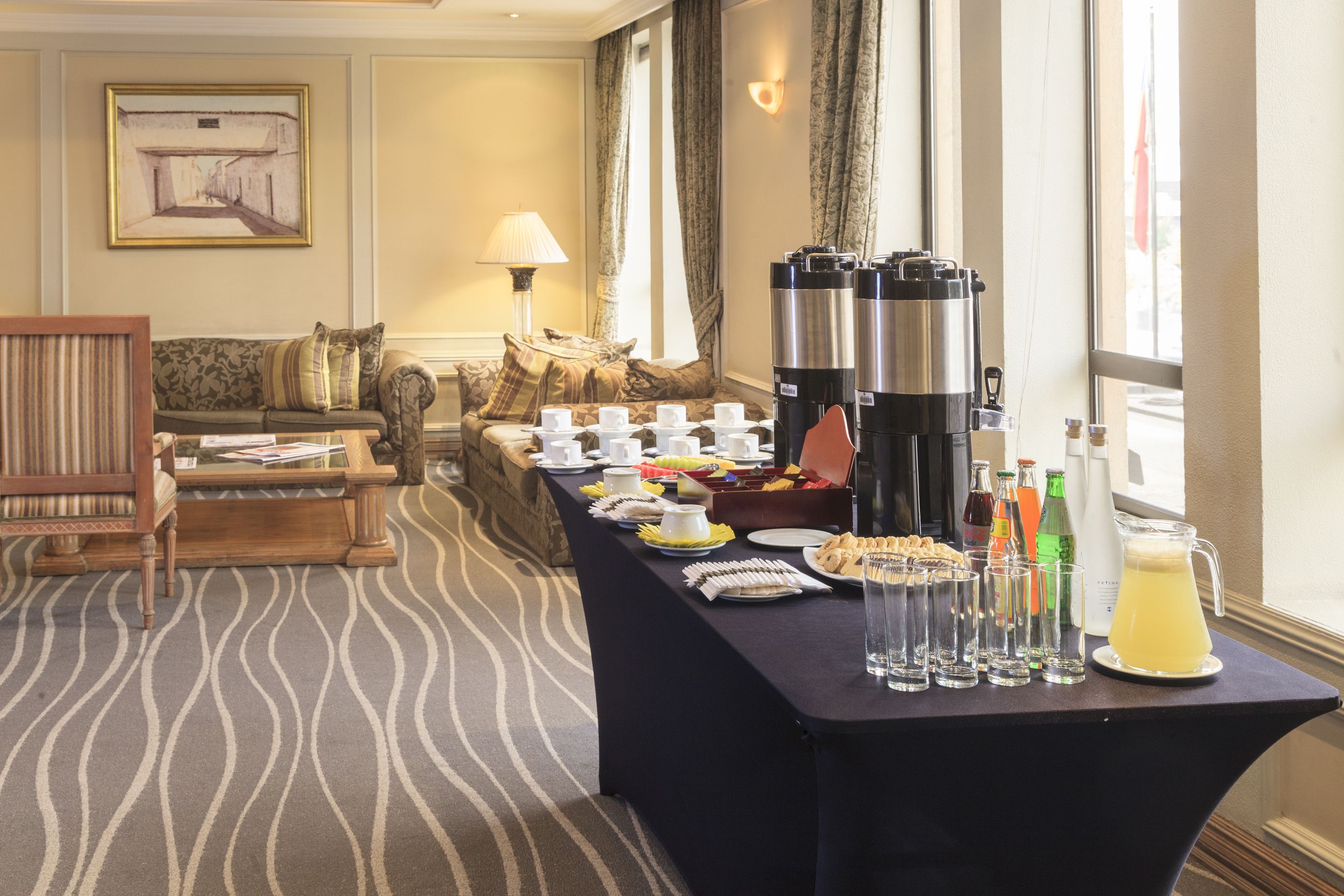 Habitación de hotel con una mesa de comedor dispuesta para el desayuno, un sofá y una lámpara.