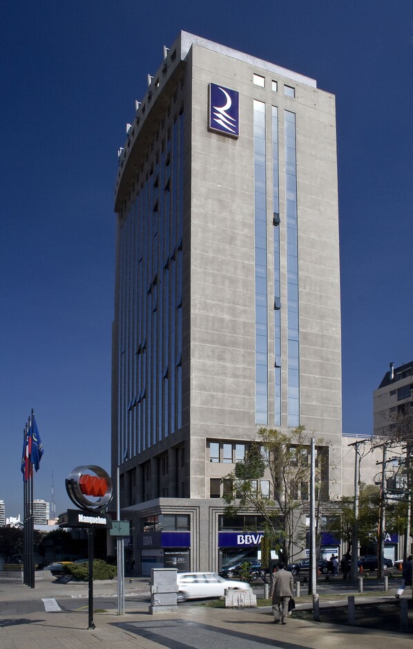 A tall building with a prominent logo on the side, a sign for 'Manquehue', and a 'BEV' sign below.