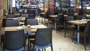 An indoor dining area with tables and chairs, ceiling artwork, and large windows overlooking a street. - Regal Pacific Hotel Santiago (Santiago)