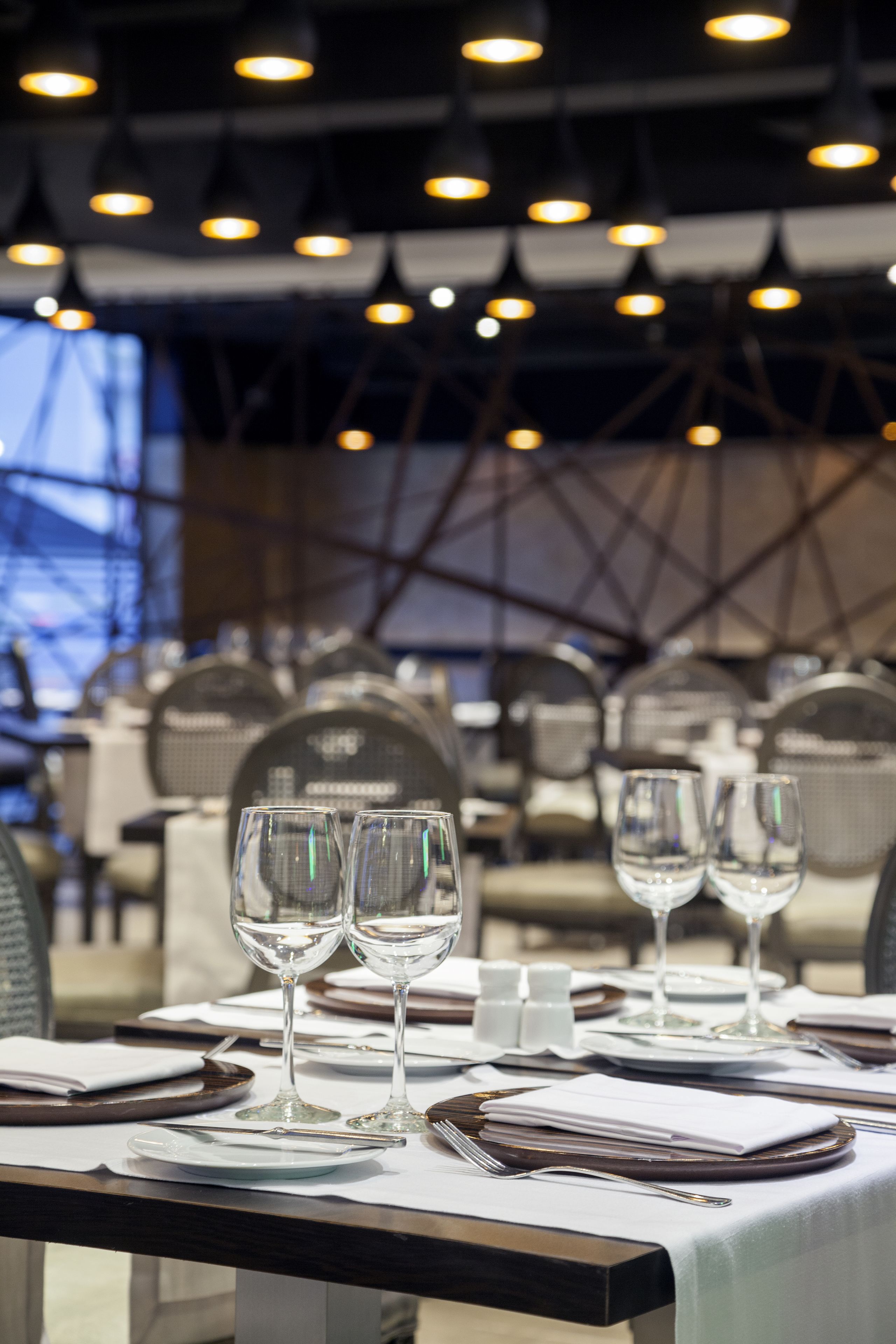Un'ambientazione da ristorante con tavoli apparecchiati per consumare, con bicchieri e piatti trasparenti.