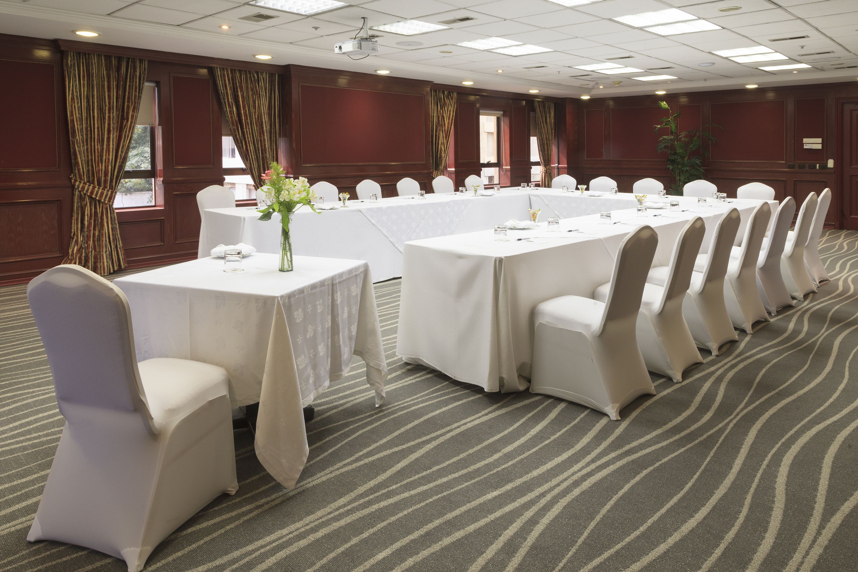 A conference room with a long table, white chairs, and a carpeted floor.