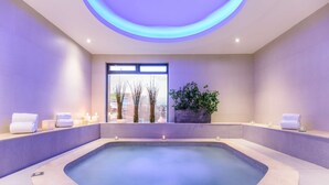 A modern spa with a large oval pool, a potted plant, and candles on a shelf. - NH Collection Bogotá Teleport Royal (Bogotá)