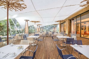 Enjoy a casual dining experience under a shaded canopy with tables set for a meal.