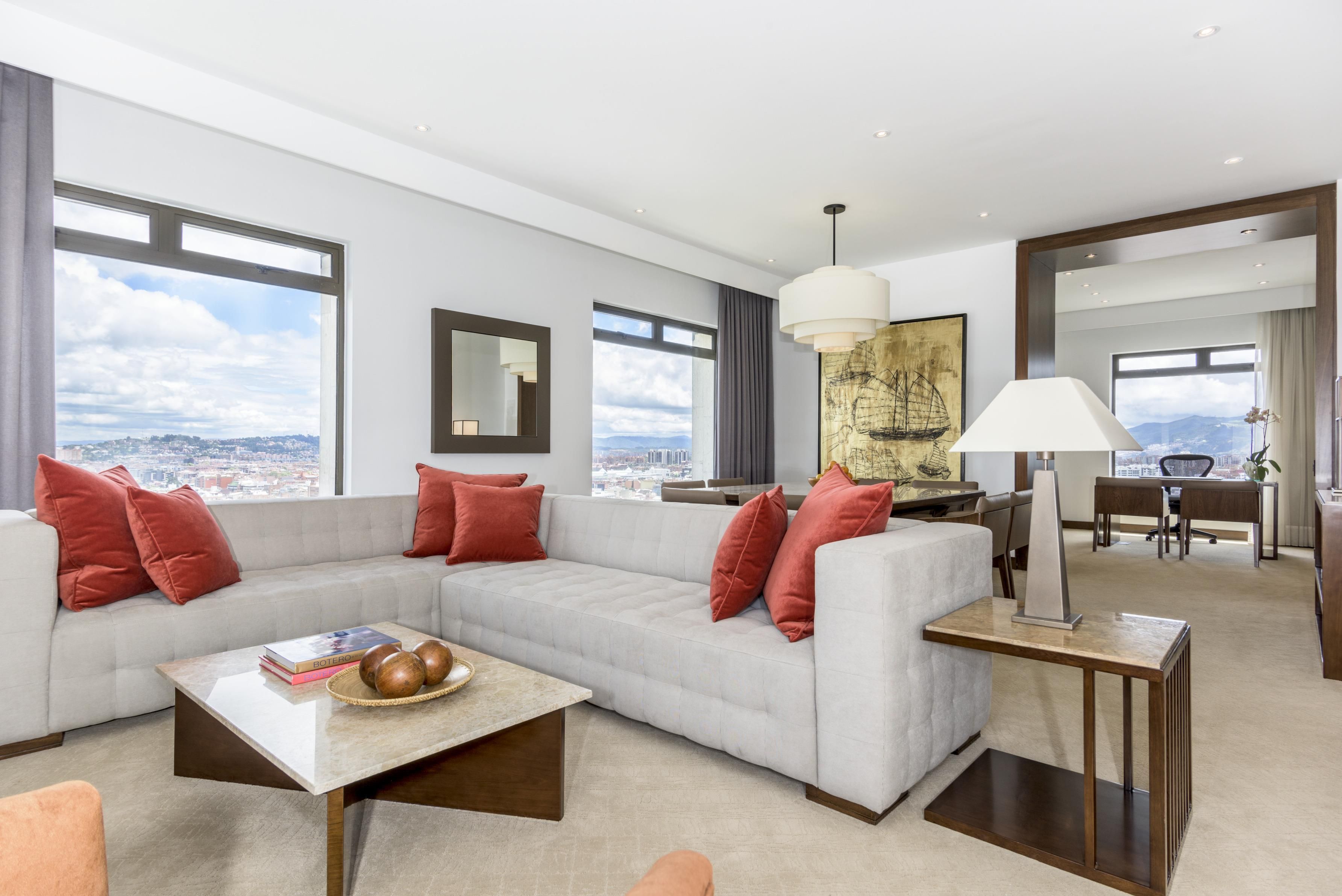 A modern living room with a sectional sofa, a coffee table, and a view of the city.
