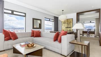 A modern living room with a sectional sofa, a coffee table, and a view of the city.