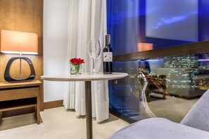 A hotel room with a round table, a bottle of wine, a glass, and a vase with flowers. - NH Collection Bogotá Teleport Royal (Bogotá)