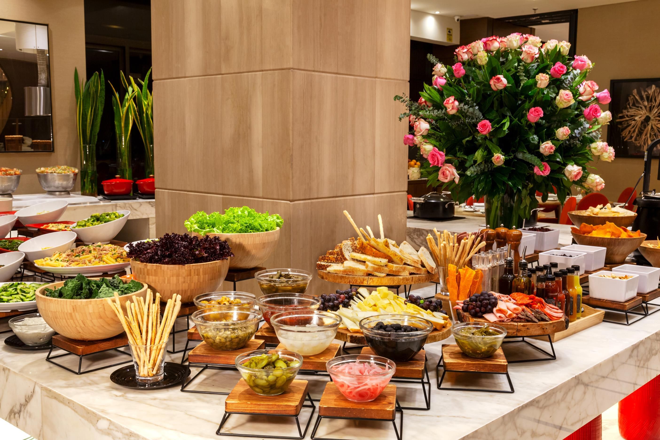 A buffet with various food items and a large floral centerpiece.