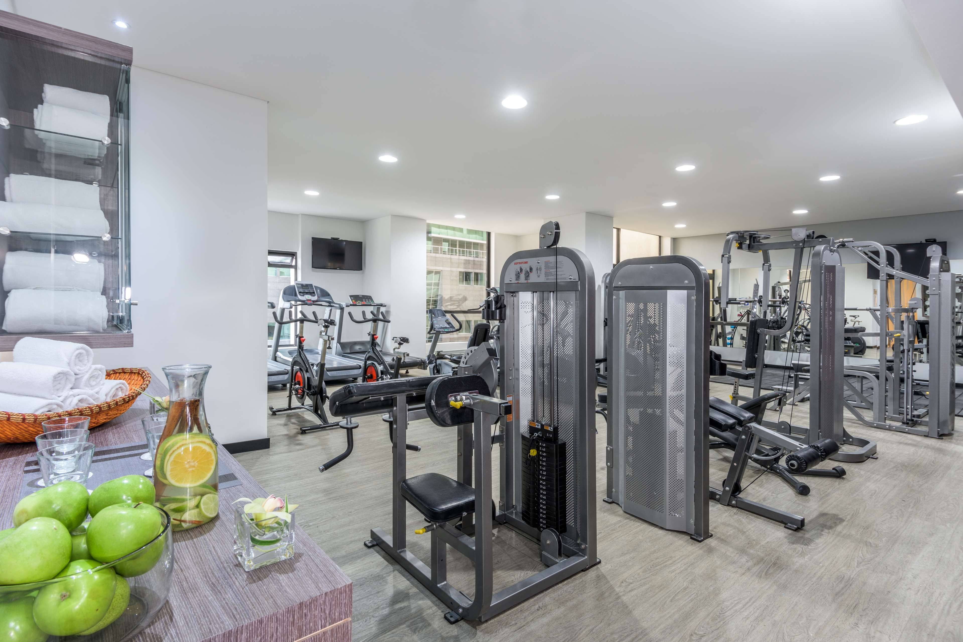 A gym with various exercise equipment, a television, and a wall-mounted towel rack.