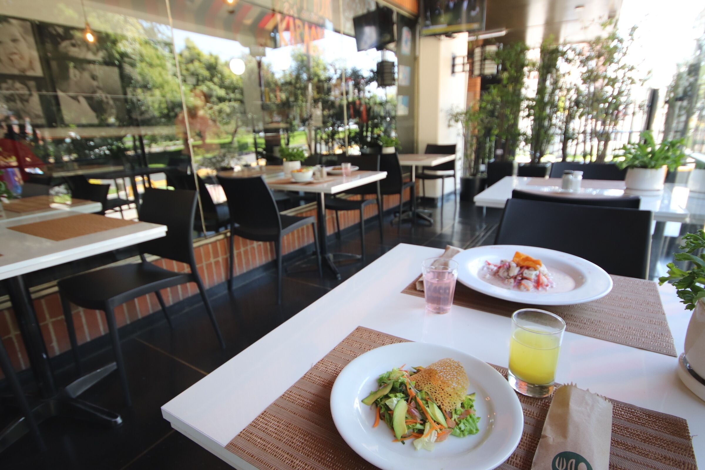 Un restaurant avec des tables et des chaises, une assiette de nourriture, une boisson et un menu.