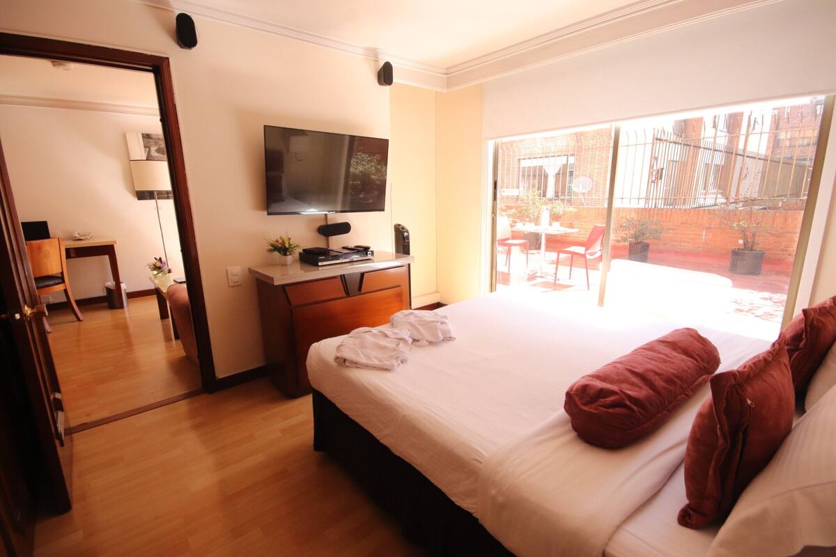 Una habitación de hotel con cama, escritorio, televisor y vistas al exterior.