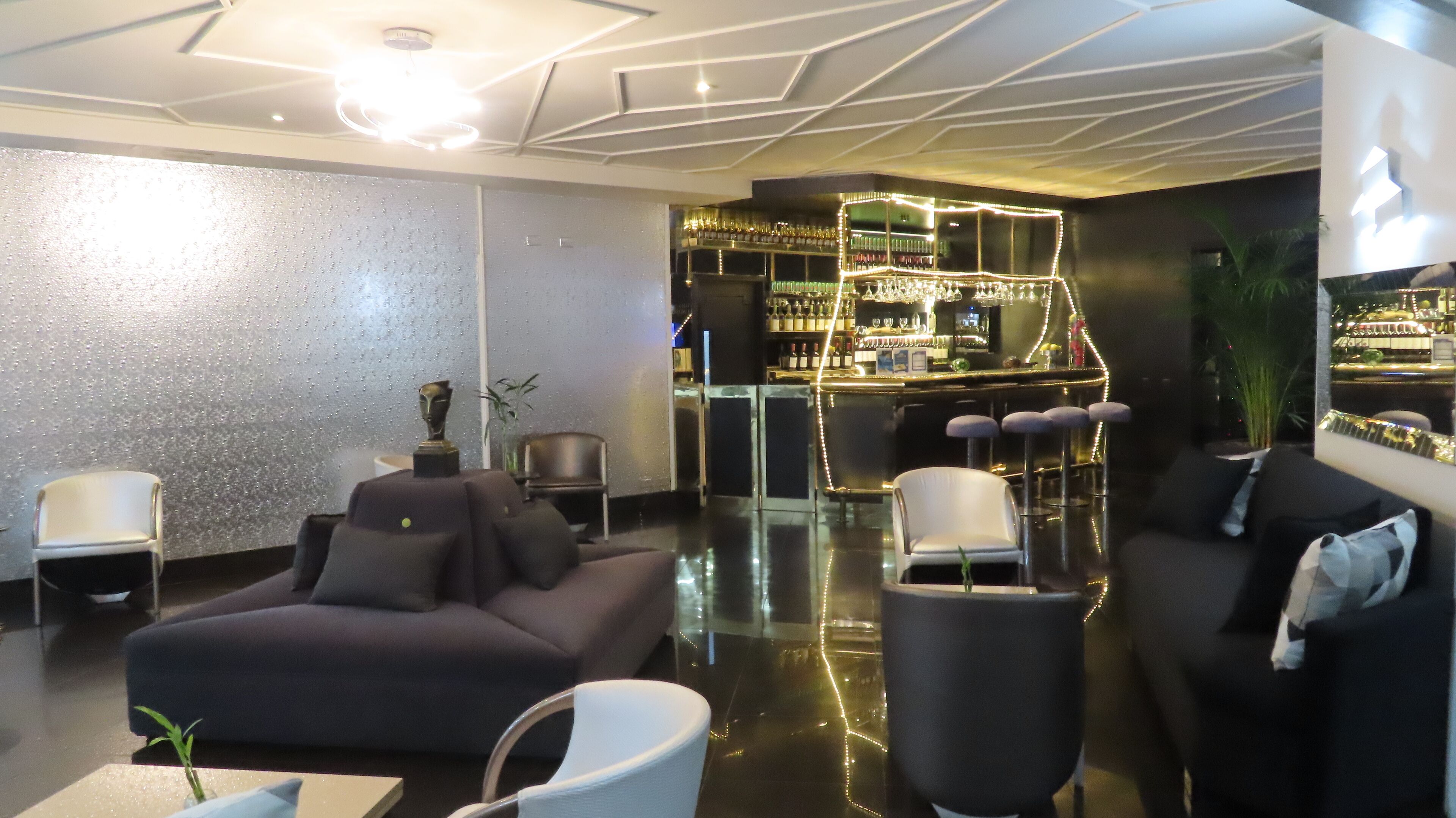 Un espace lounge moderne doté d’un bar, de canapés et de tabourets de bar.
