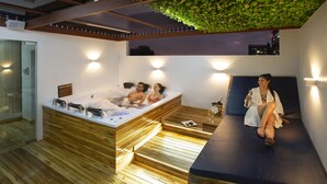 Een moderne spa ruimte met een houten vloer, een jacuzzi en een massagetafel.