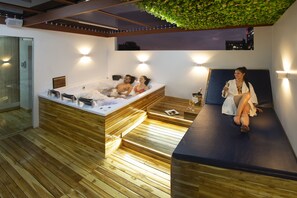 A modern spa room with a wooden floor, a hot tub, and a massage table. - Lancaster House (Bogotá)