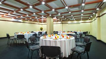 A conference room with round tables, chairs, and a high ceiling with exposed beams.