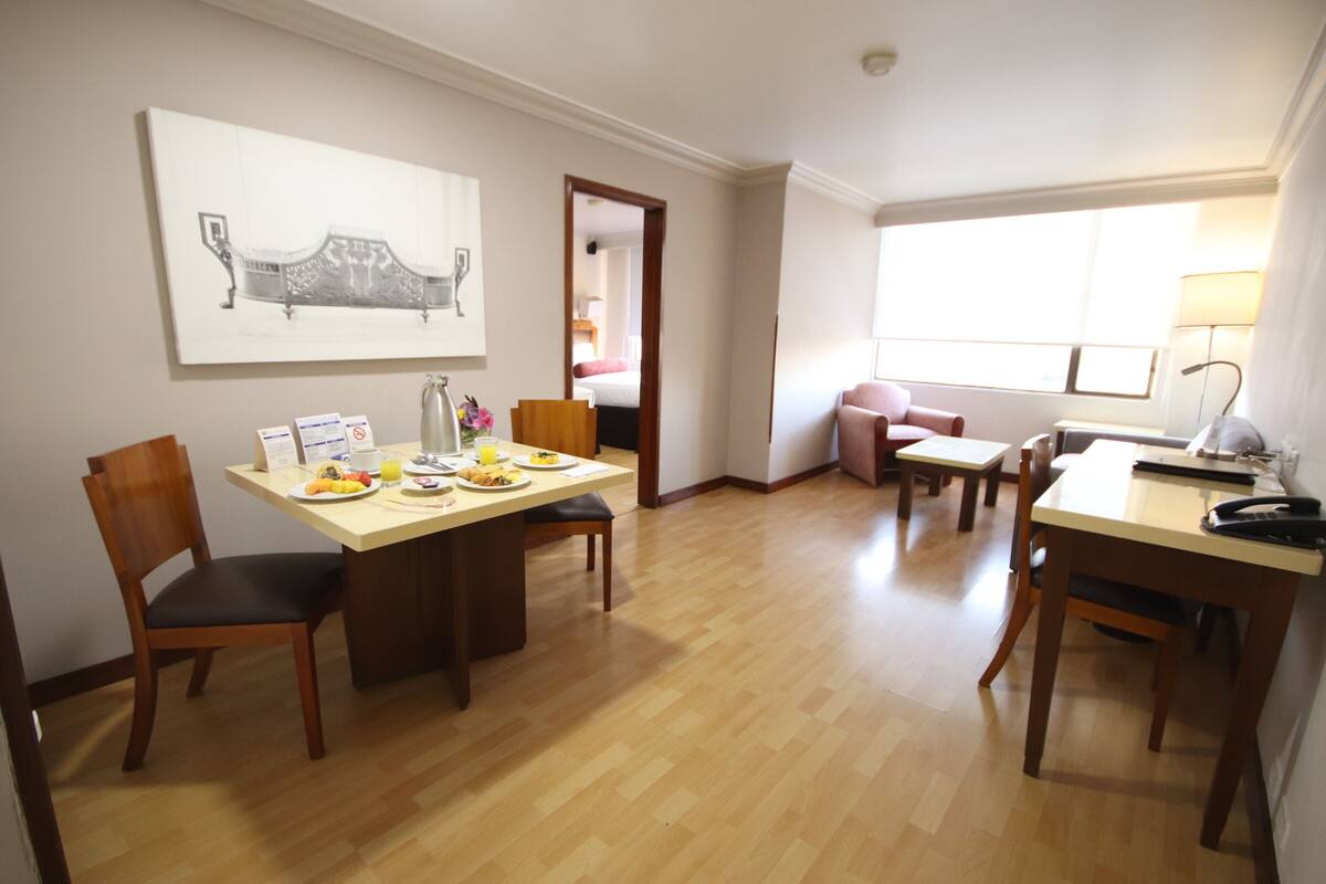 Un comedor con una mesa de madera, sillas y un cuadro en la pared.