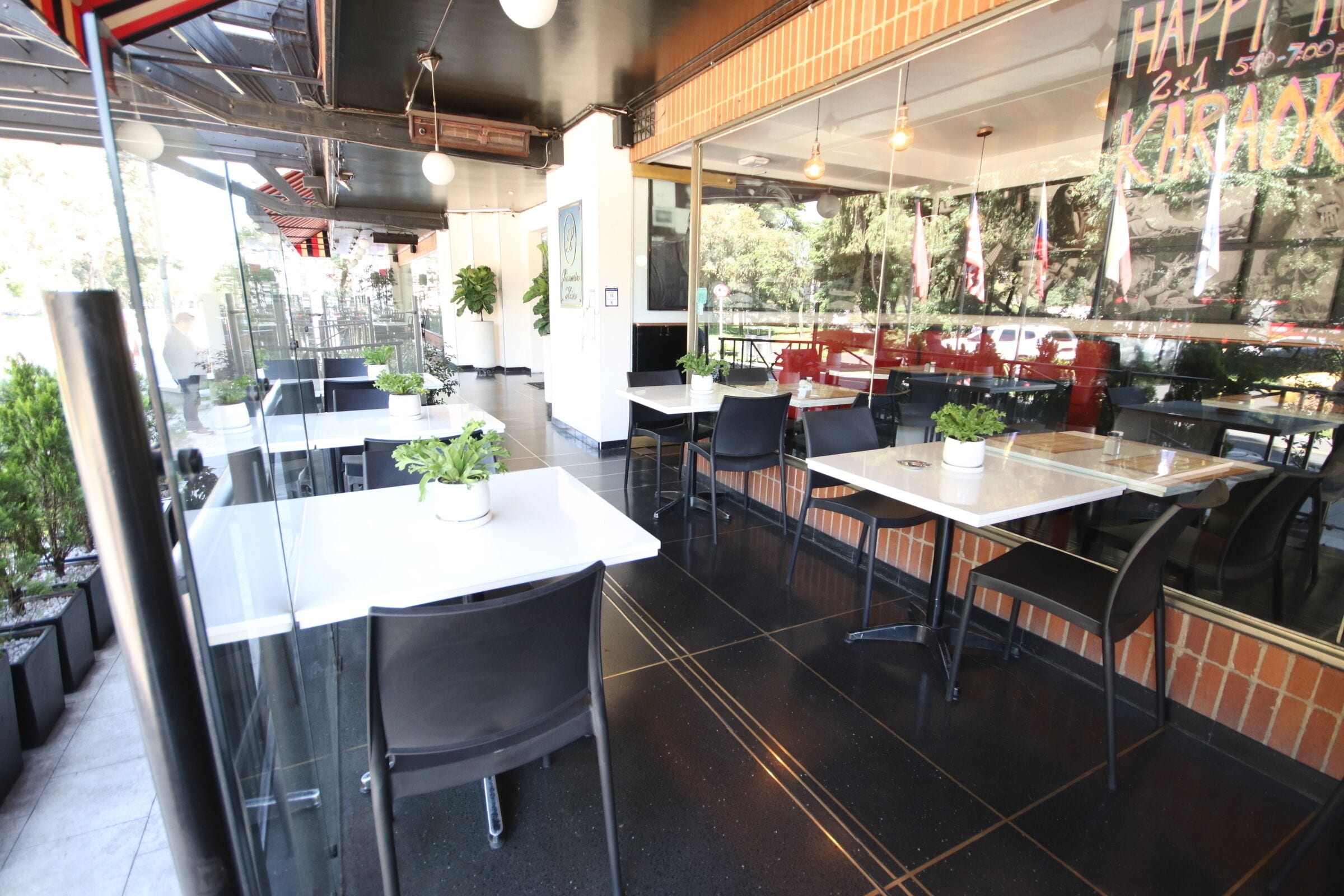An indoor dining area with tables and chairs, potted plants, and a brick wall.