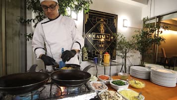 Un chef con uniforme blanco cocina en una estufa, con varios platos e ingredientes sobre la mesa.