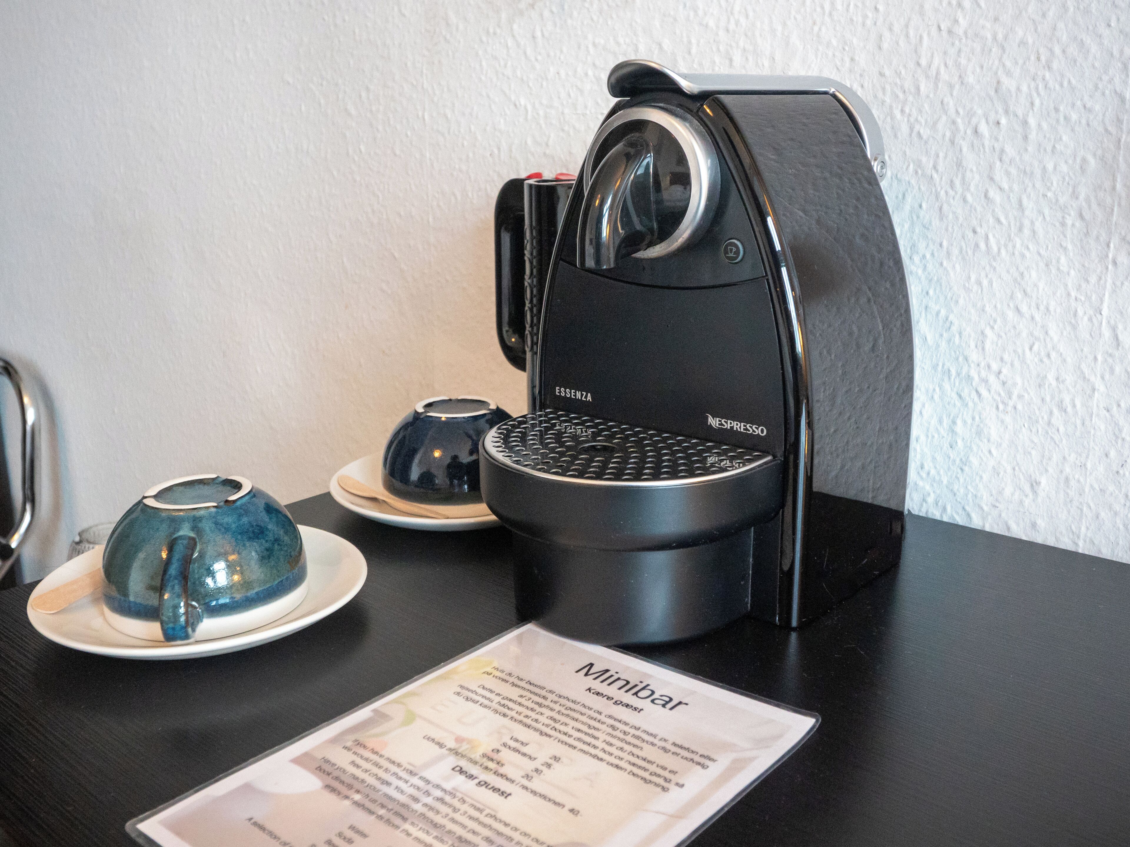 A Nespresso coffee machine on a table with a menu and a cup of coffee.