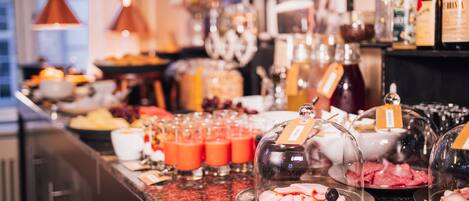 Un bufé con diversas opciones de comida y bebidas, como carnes frías, frutas y jugos.