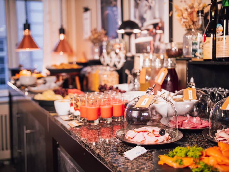 Un bufé con diversas opciones de comida y bebidas, como carnes frías, frutas y jugos.