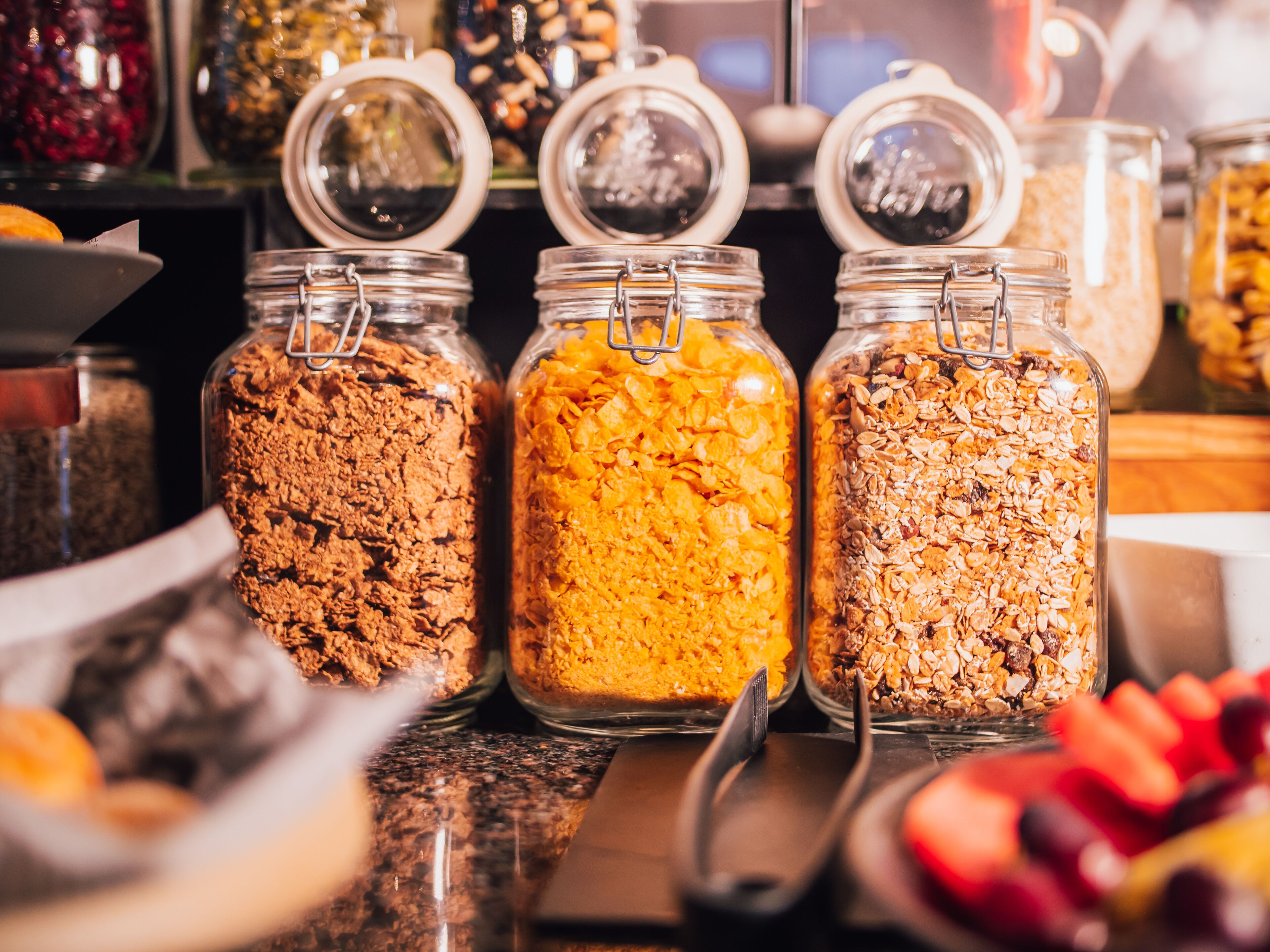 Tre barattoli di vetro con chiusure metalliche, contenenti diversi tipi di granola.