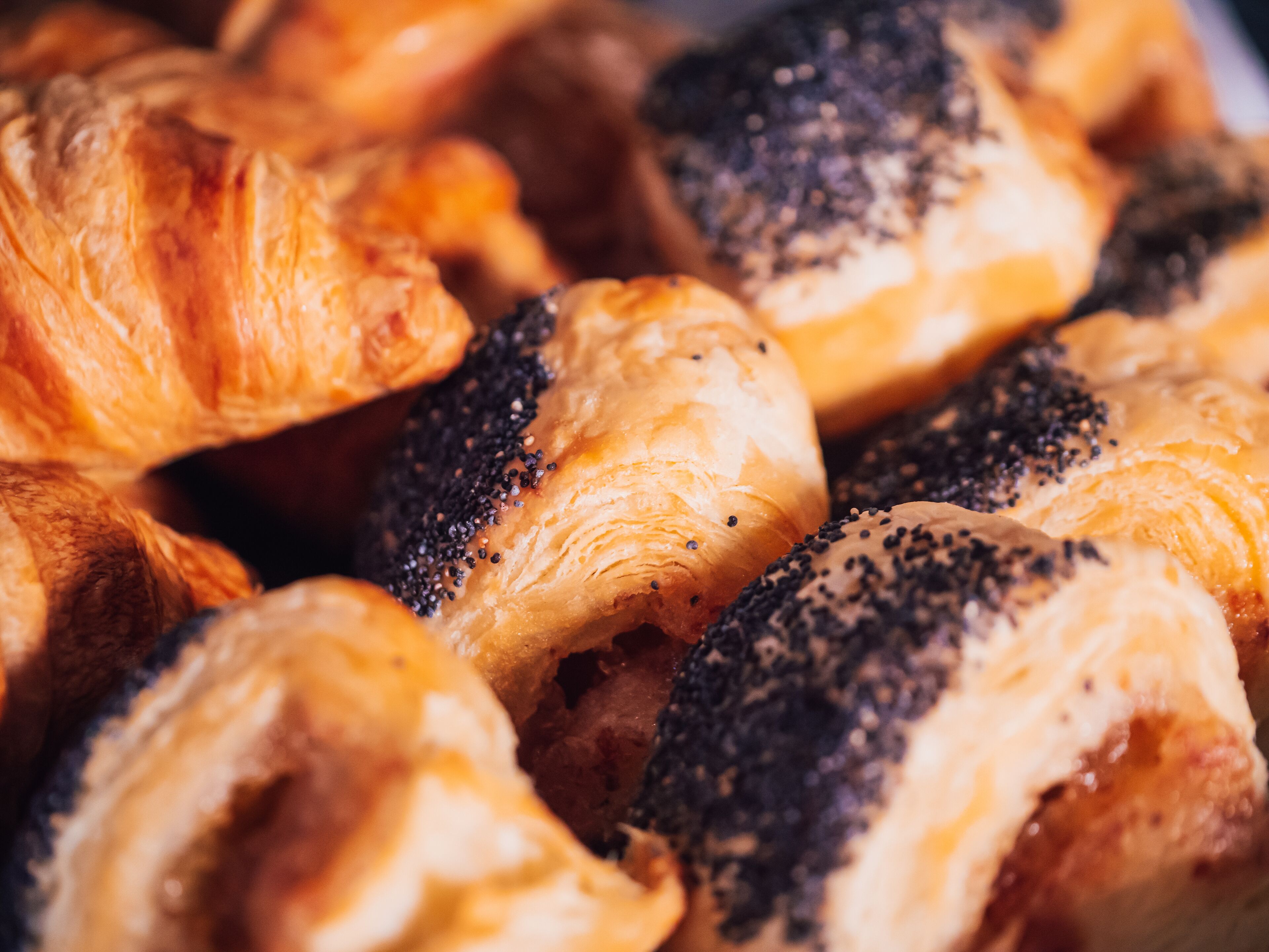 A close-up of various pastries, including croissants and poppy seed rolls.