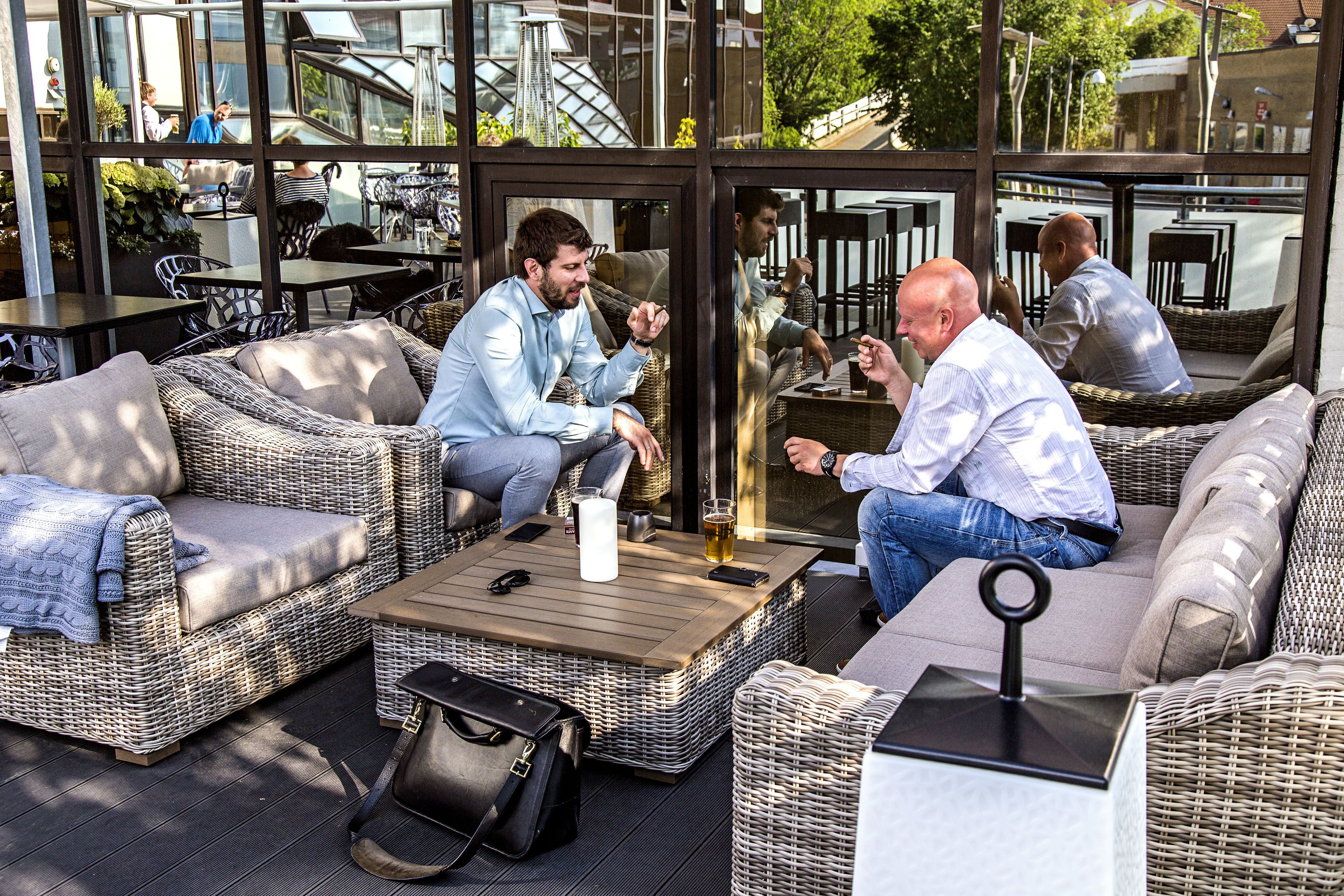 An outdoor seating area with wicker furniture and a glass enclosure.