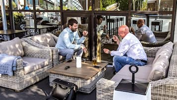 An outdoor seating area with wicker furniture and a glass enclosure.