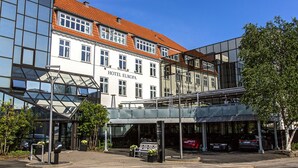 A modern hotel with a glass facade, a red-tiled roof, and a covered entrance area. - Hotel Europa (Aabenraa)