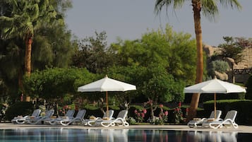 Una piscina al aire libre, sombrillas, tumbonas