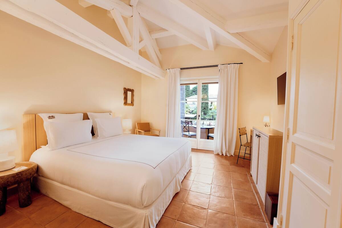Un dormitorio con una cama grande, un escritorio, una silla y vistas al exterior.